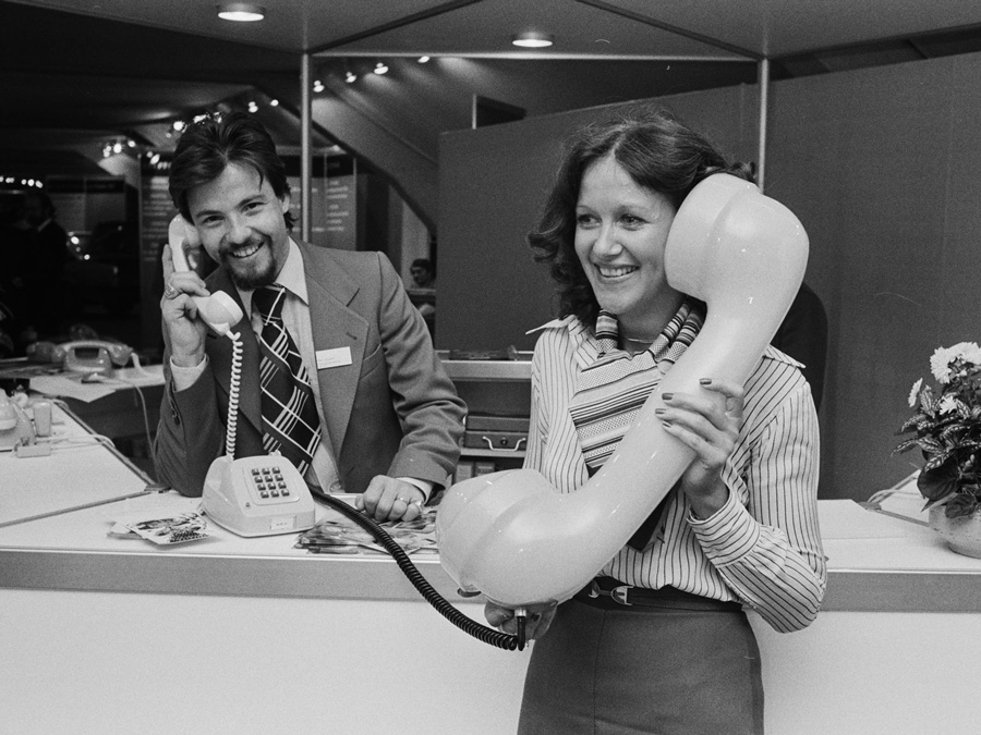 Mann und Frau an Reception mit überdimensionalem Telefonhörer
