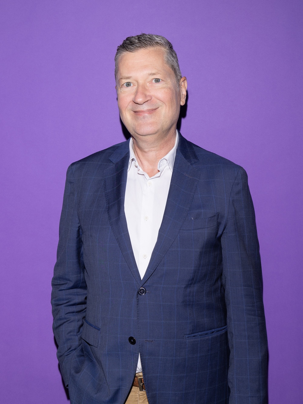 Porträt von Pius Sidler. Mann mit dunkelblauem Blazer auf violettem Hintergrund.