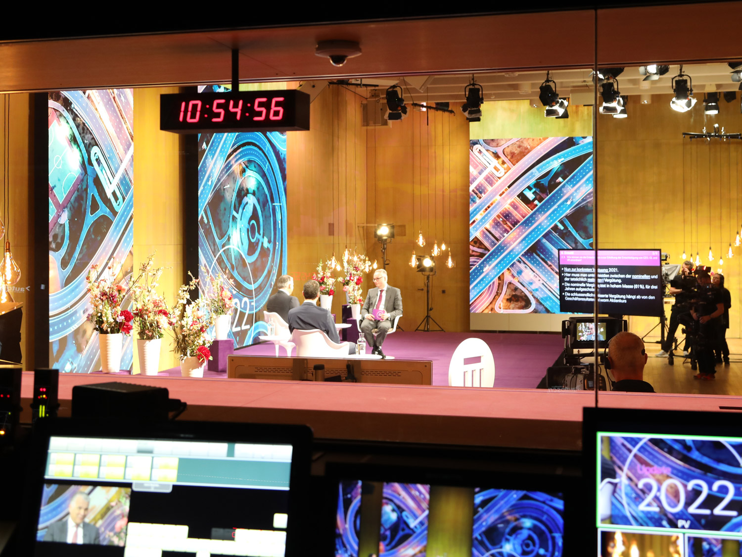 Blick aus der Regie in eine Halle mit drei Männern auf einer Bühne.